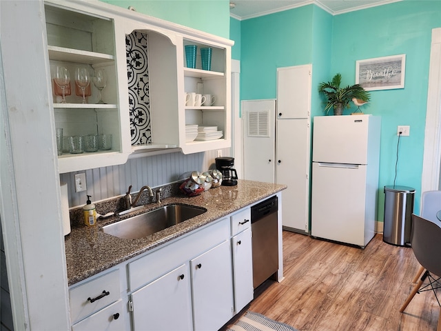 kitchen with dark stone countertops, sink, ornamental molding, white fridge, and white cabinetry