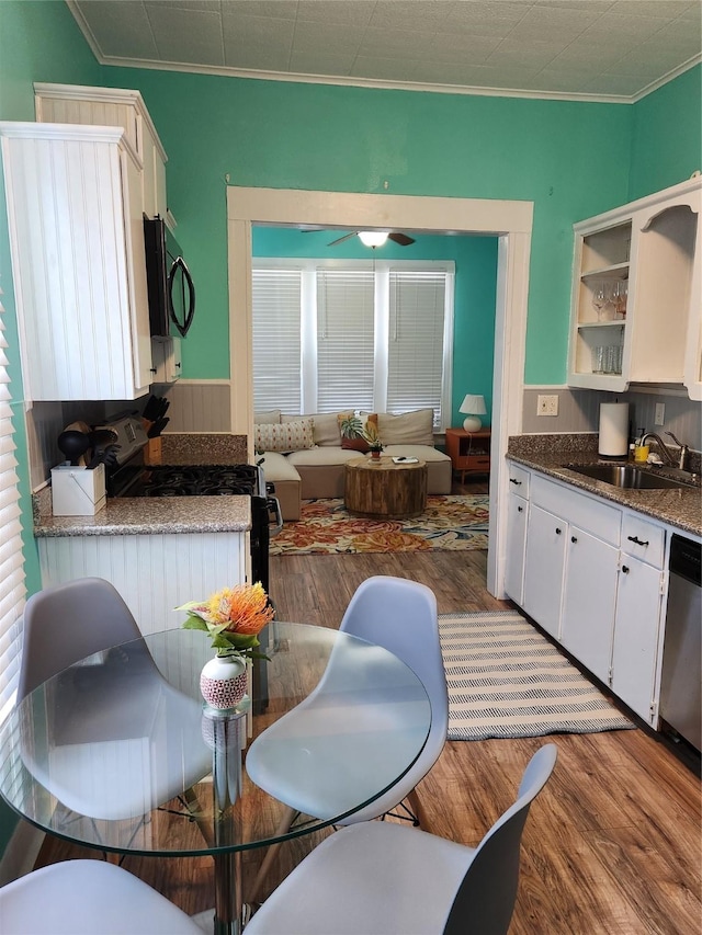 2219 33rd St E, Galveston, TX 77550 - kitchen with crown molding, a sink, white cabinetry, wood finished floors, and black appliances