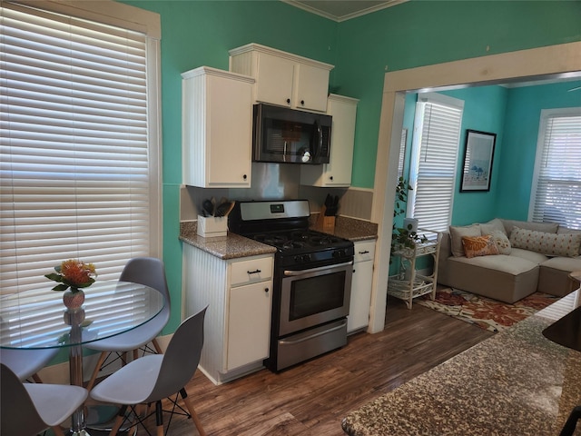 2219 33rd St E, Galveston, TX 77550 - kitchen featuring black microwave, crown molding, gas stove, dark wood-style floors, and white cabinetry