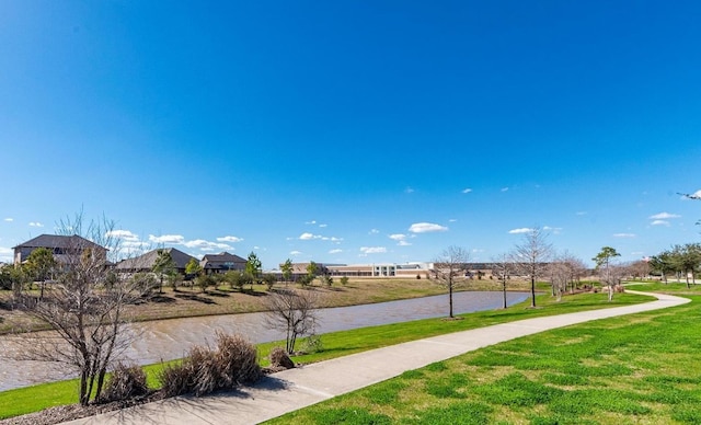 view of property's community with a water view and a lawn