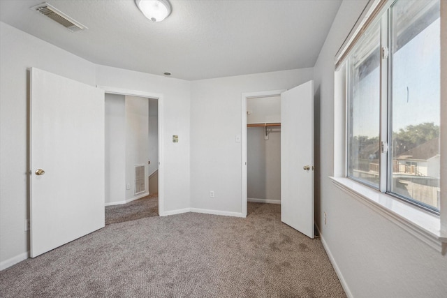 unfurnished bedroom featuring a spacious closet, carpet floors, and a closet