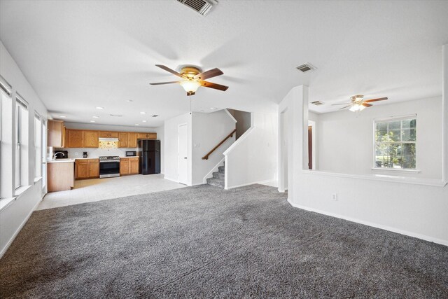 unfurnished living room featuring light colored carpet and ceiling fan