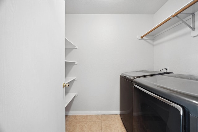 laundry area with washer and clothes dryer and light tile patterned floors