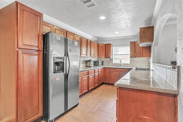 kitchen with a textured ceiling, backsplash, ornamental molding, and appliances with stainless steel finishes