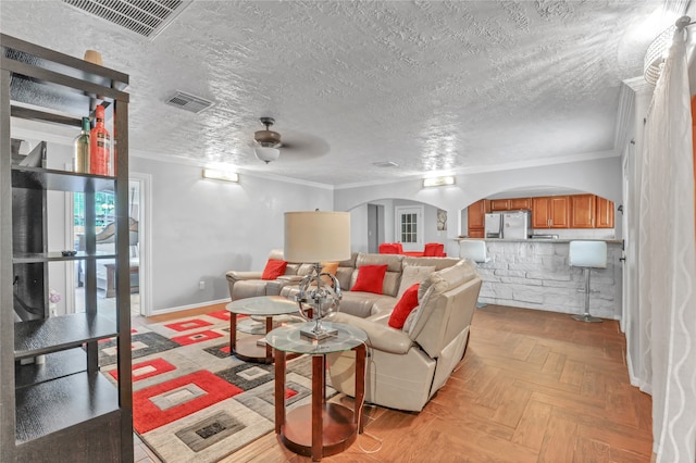 living room featuring light parquet floors, crown molding, ceiling fan, and a textured ceiling