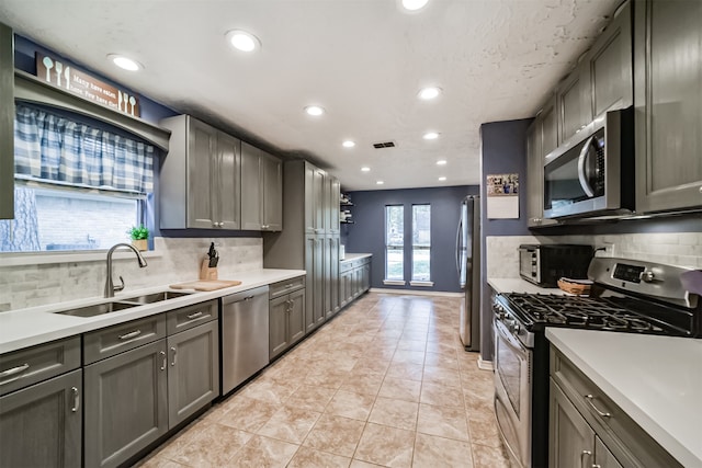 kitchen featuring appliances with stainless steel finishes, backsplash, sink, and light tile patterned flooring