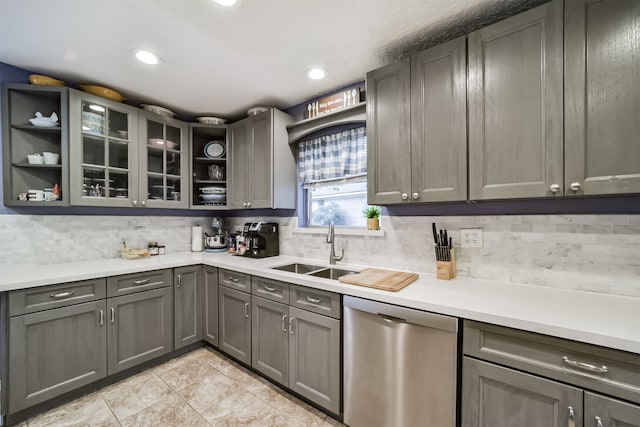 kitchen featuring gray cabinetry, light tile patterned floors, dishwasher, sink, and decorative backsplash