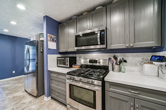 kitchen with gray cabinetry, stainless steel appliances, tasteful backsplash, and a textured ceiling