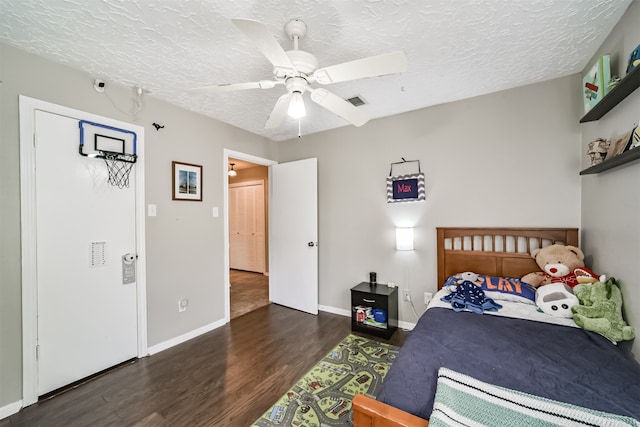 bedroom with a textured ceiling, ceiling fan, and dark hardwood / wood-style flooring