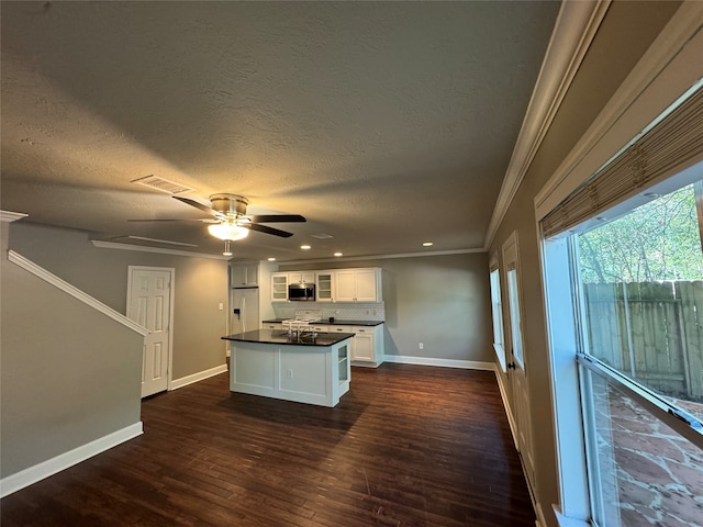 kitchen with white cabinets, ornamental molding, a textured ceiling, and dark wood-type flooring