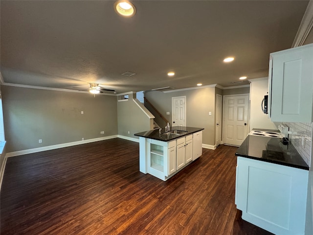 kitchen featuring tasteful backsplash, ornamental molding, dark wood-type flooring, white cabinets, and a kitchen island