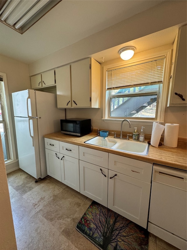 kitchen featuring white appliances, white cabinetry, and sink