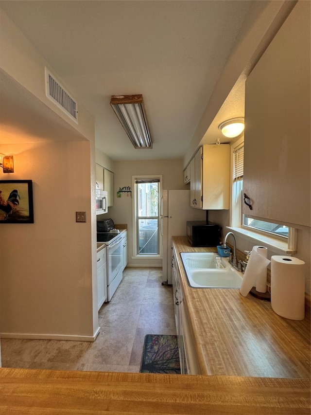 kitchen featuring white electric stove, white cabinetry, and sink