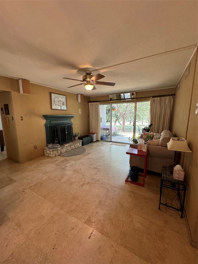 living room featuring ceiling fan, a textured ceiling, and a fireplace