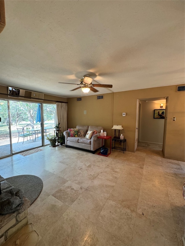 living room featuring ceiling fan and a textured ceiling