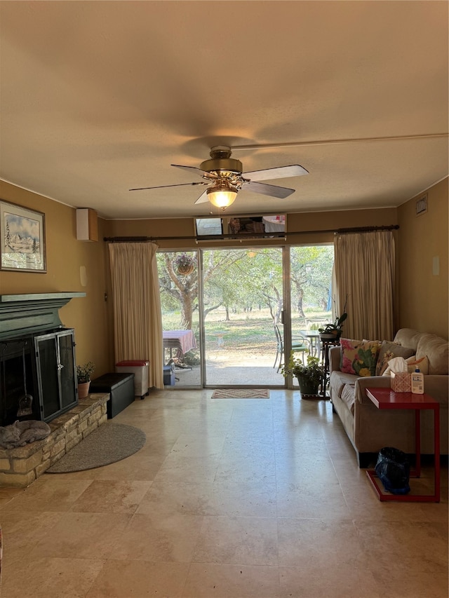 living room with a healthy amount of sunlight, a stone fireplace, and ceiling fan