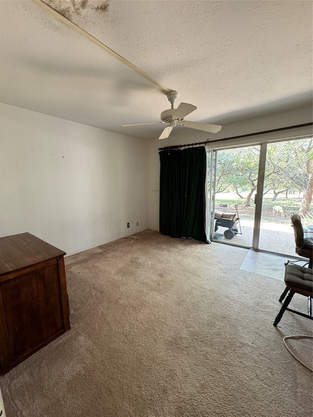 interior space with ceiling fan, a textured ceiling, and carpet floors