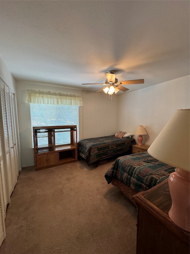 bedroom featuring carpet, a closet, ceiling fan, and a textured ceiling