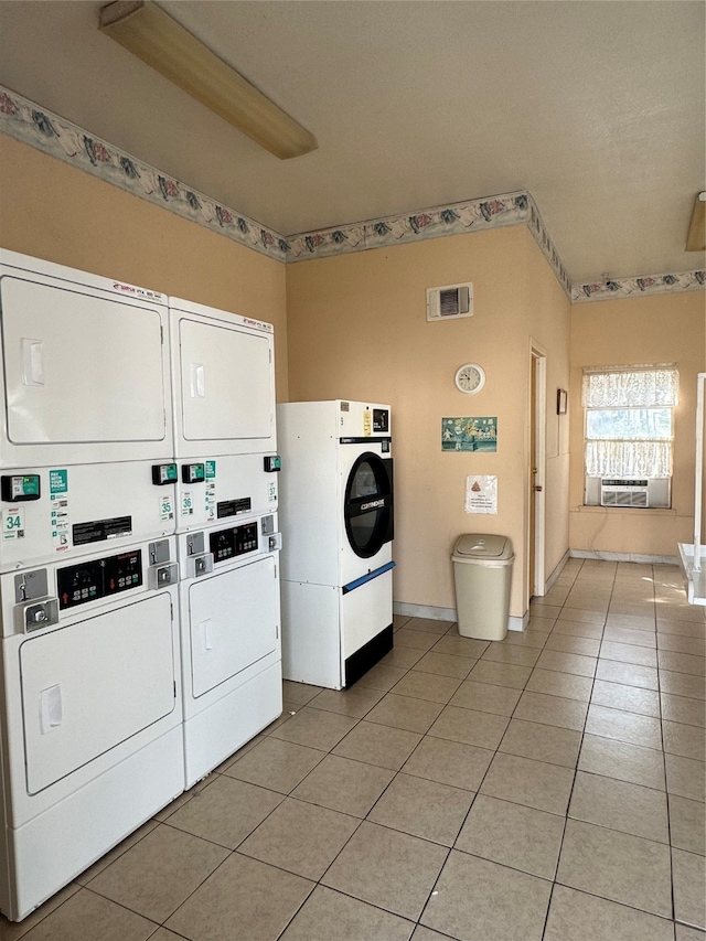 clothes washing area featuring cooling unit, light tile patterned flooring, and stacked washer and dryer