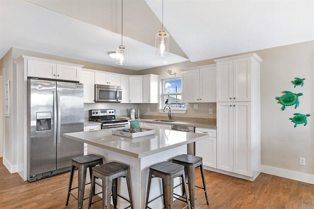 kitchen with light hardwood / wood-style floors, a center island, stainless steel appliances, sink, and white cabinetry