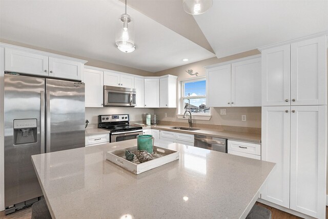 kitchen featuring sink, decorative light fixtures, appliances with stainless steel finishes, and white cabinets