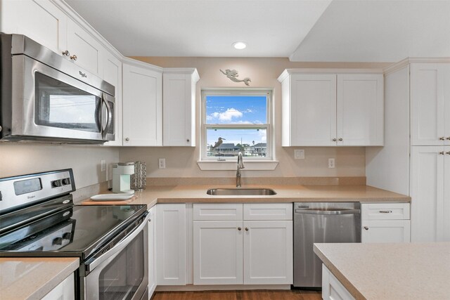 kitchen with light wood-type flooring, sink, appliances with stainless steel finishes, and white cabinetry