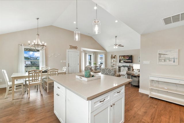 kitchen with pendant lighting, hardwood / wood-style floors, ceiling fan with notable chandelier, vaulted ceiling, and white cabinets