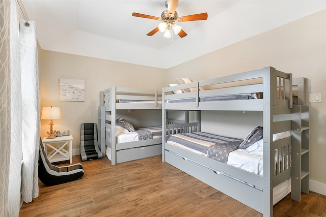 bedroom featuring a raised ceiling, ceiling fan, and hardwood / wood-style flooring