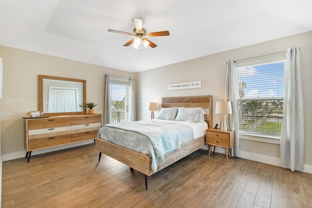 bedroom with hardwood / wood-style flooring, ceiling fan, and multiple windows