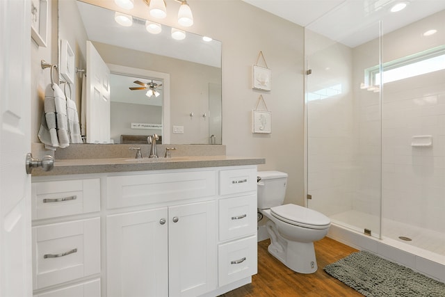 bathroom with toilet, walk in shower, vanity, ceiling fan, and hardwood / wood-style flooring