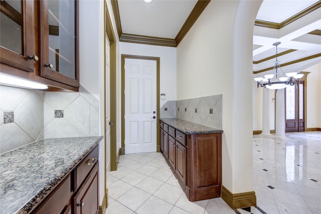 kitchen featuring ornamental molding, a notable chandelier, light stone countertops, and backsplash