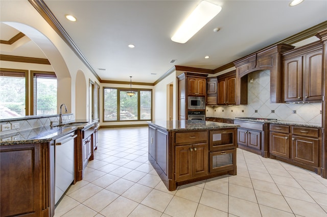 kitchen featuring a kitchen island with sink, stainless steel appliances, ornamental molding, dark stone countertops, and light tile patterned flooring