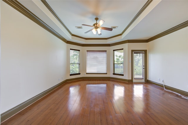 empty room featuring a wealth of natural light, ceiling fan, ornamental molding, and hardwood / wood-style flooring