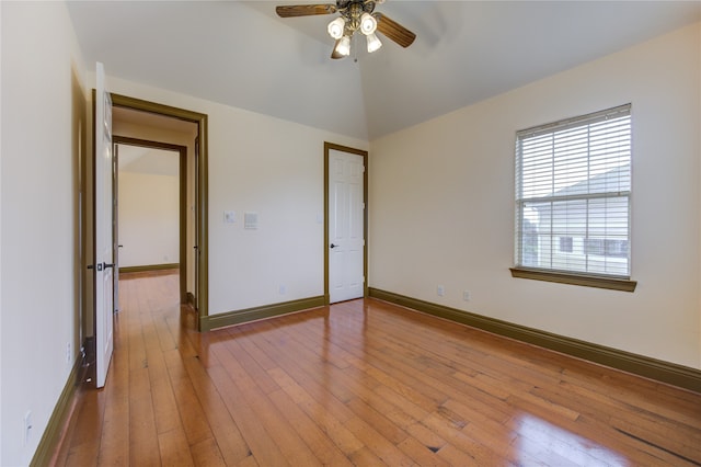 empty room with lofted ceiling, light hardwood / wood-style flooring, and ceiling fan