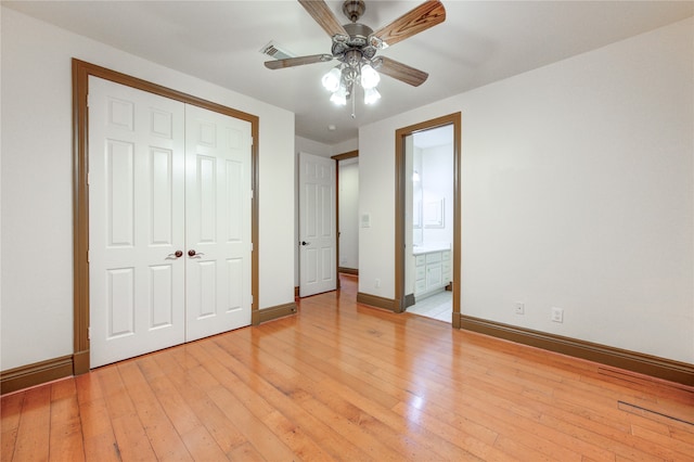 unfurnished bedroom with a closet, ceiling fan, ensuite bath, and light wood-type flooring