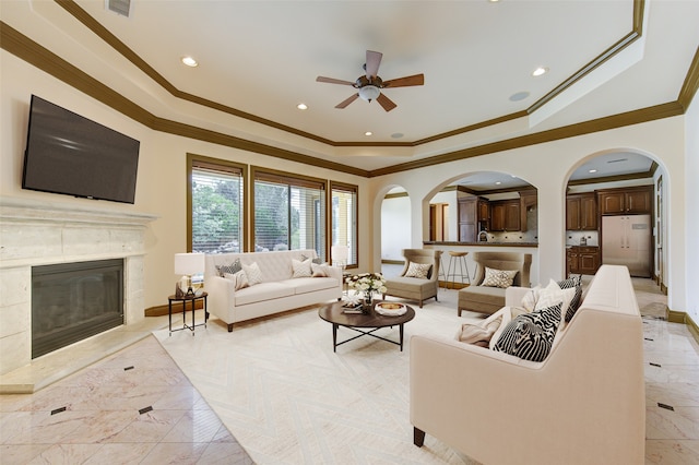 living room featuring crown molding, ceiling fan, and a premium fireplace