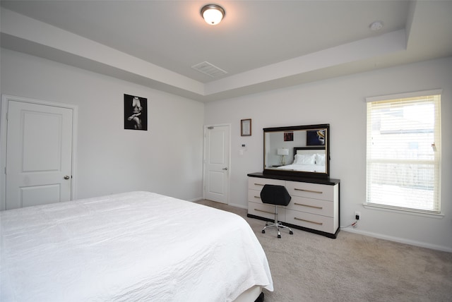 bedroom with light carpet and a tray ceiling