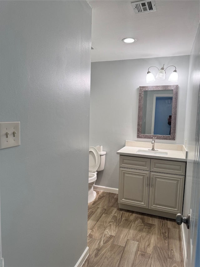 bathroom with vanity, toilet, and hardwood / wood-style floors