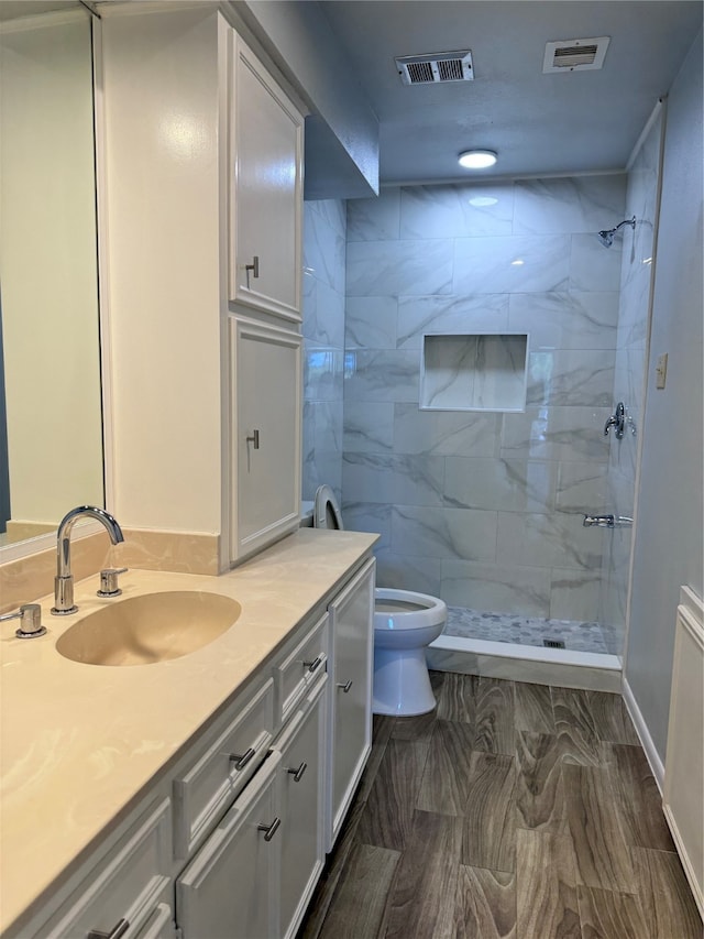 bathroom with vanity, toilet, and a tile shower