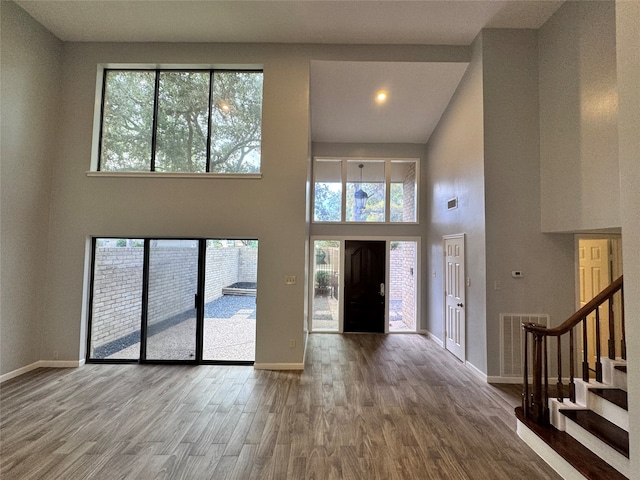 foyer featuring wood-type flooring and a towering ceiling