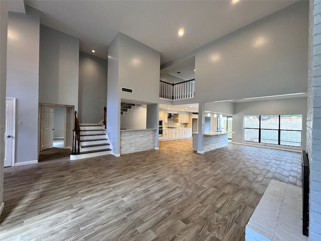 unfurnished living room with a high ceiling and wood-type flooring