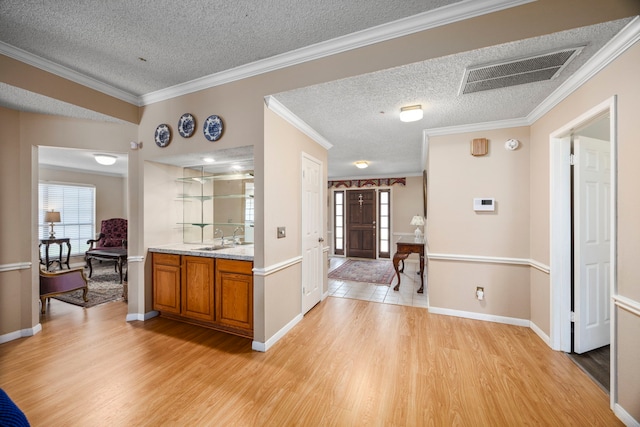 interior space with a textured ceiling, light wood-type flooring, and ornamental molding