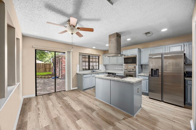 kitchen with appliances with stainless steel finishes, light wood-type flooring, island range hood, a center island, and gray cabinets