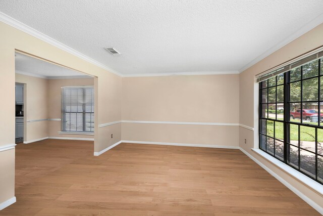 spare room featuring ornamental molding, a textured ceiling, and light wood-type flooring