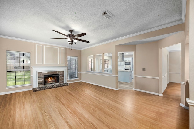 unfurnished living room with a textured ceiling, light hardwood / wood-style floors, a brick fireplace, and ornamental molding