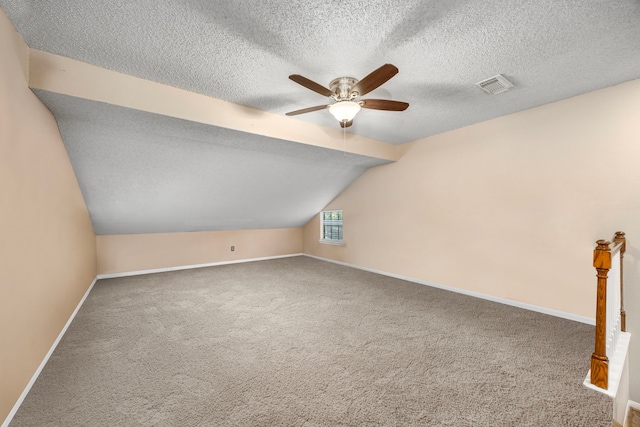 bonus room with lofted ceiling, ceiling fan, carpet, and a textured ceiling