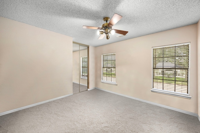 carpeted empty room with a textured ceiling and ceiling fan