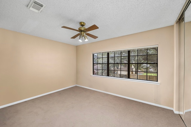 unfurnished room with carpet flooring, a textured ceiling, and a wealth of natural light