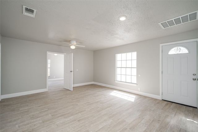 foyer entrance with light wood-type flooring, a textured ceiling, and ceiling fan