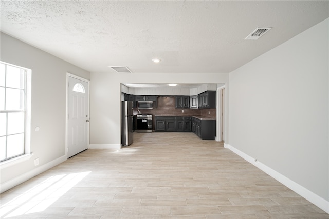 unfurnished living room featuring a textured ceiling and light hardwood / wood-style flooring